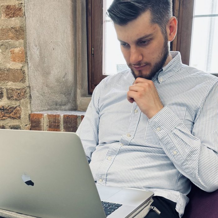 Mitarbeiter der Google-Ads-Agentur Ein Mitarbeiter von OMNI2 entwickelt eine Google Ads-Strategie am Laptop und hält nachdenklich seine Hand ans Kinn.